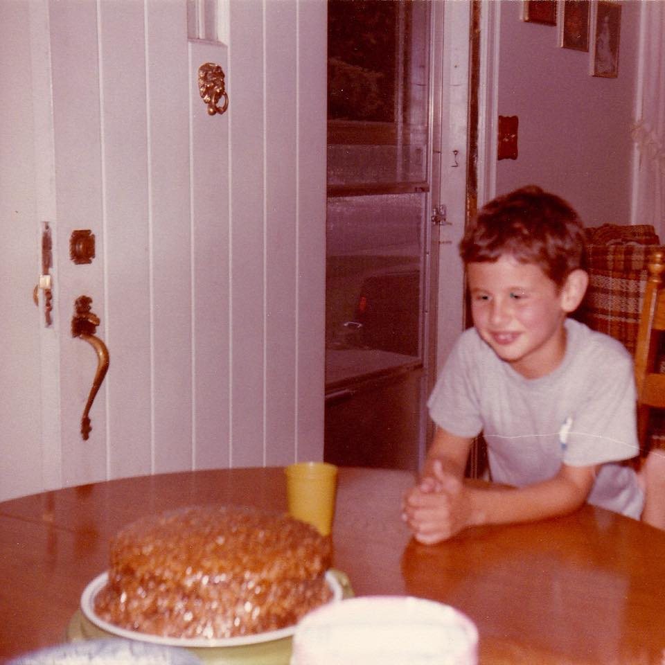 Massimo as a young boy at a kitchen table with a birthday cake